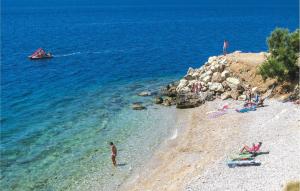 a group of people on a beach with a boat in the water at Apartment Zivkovic in Rogoznica