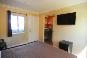 1 dormitorio con 1 cama y TV en la pared en Studio City Inn - Near Universal Studios Hollywood en Los Ángeles