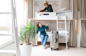 a woman sitting in a bunk bed with a suitcase at Casa Blanca Guesthouse in Nagasaki