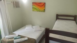 two beds in a room with a painting on the wall at Sun Suítes in Ubatuba