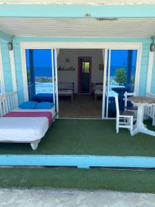 a porch with two beds and a table and chairs at El Embrujo Tintipan in Tintipan Island