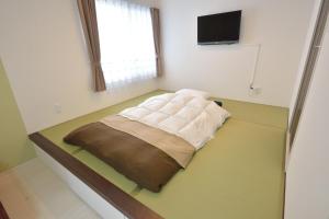 Bett in einem Zimmer mit einem TV an der Wand in der Unterkunft Guest House Gifuhashima COCONE / Vacation STAY 33938 in Hashima