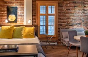 a living room with a couch and a brick wall at Appart-Hôtel Le Vincent in Quebec City