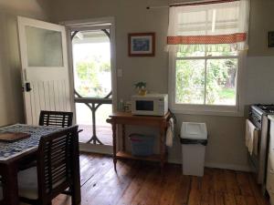 a kitchen with a table with a microwave and a window at Glenlyon Dam Holiday Cottage & Farmstay in Stanthorpe