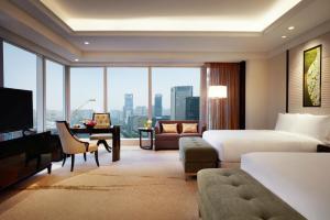 a hotel room with a bed and a desk and a room with a view at Fairmont Chengdu in Chengdu