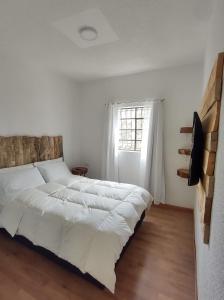 a white bedroom with a large bed and a window at Hacienda El Castillo Hotel Boutique in Pasto