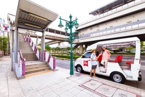 a man and a woman standing next to a white van at Ibis Bangkok Riverside in Bangkok