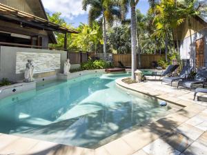 a swimming pool in a backyard with chairs and trees at Pure Magnetic Villa 9 in Nelly Bay