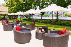 a group of chairs and umbrellas with red pillows at Ibis Bangkok Riverside in Bangkok