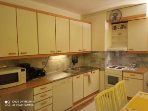 a kitchen with white cabinets and a sink and a microwave at Apartment Haltijantie in Kotka