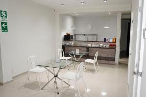a dining room with a glass table and white chairs at Hotel Kusnaya in Piura