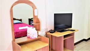 a bedroom with a bed and a tv and a mirror at Baan Yuyuen in Pathum Thani