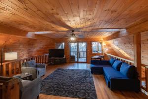 un soggiorno con soffitti in legno e divano blu di Treetops Cabin easy to Asheville with fast wifi and great view a Swiss
