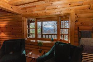 a living room with a window in a log cabin at Treetops Cabin easy to Asheville with fast wifi and great view in Swiss