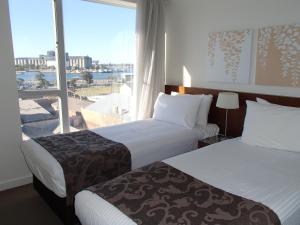 a hotel room with two beds and two windows at Newcastle Central Plaza Apartment Hotel in Newcastle