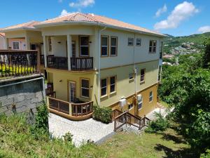 una casa gialla con balcone su una collina di Keep Cool Guesthouse a Gros Islet