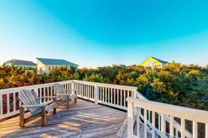 two chairs on a wooden deck with a view of a house at Under The Boardwalk in Avon