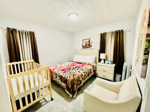 a bedroom with a bed and a crib and a chair at Newly Renovated 2 Floor Apartment Getaway in Springfield