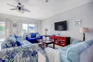 een woonkamer met blauwe banken en een flatscreen-tv bij Coconut Grove 203 in Myrtle Beach