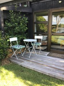 two chairs and a table on a wooden deck at Lakehouse Studio in Kerikeri