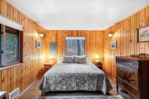 a bedroom with wooden walls and a bed and two windows at The Legacy in McCall