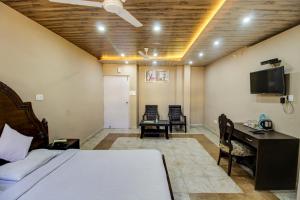FabHotel Pinjore Holiday Home في Pinjaur: غرفة نوم بسرير ومكتب وتلفزيون