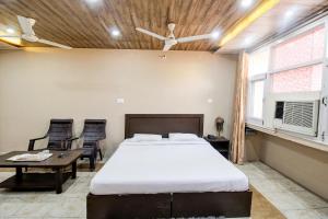 FabHotel Pinjore Holiday Home في Pinjaur: غرفة نوم بسرير وطاولة وكراسي