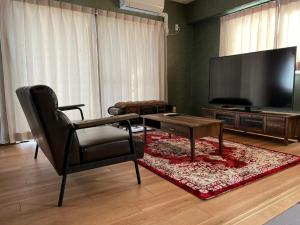 uma sala de estar com uma televisão, uma cadeira e uma mesa em Parkside Inn Hakata No5 em Fukuoka