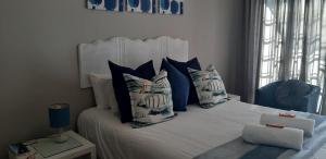 una camera da letto con un letto con cuscini blu e bianchi di Shark Cove Little Cottage a Kleinbaai
