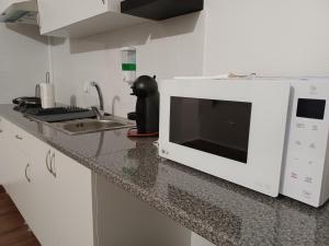 un forno a microonde seduto sopra un bancone della cucina di De Cá - suite com acesso independente e kitchenette a Lousã