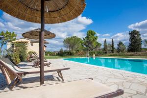 einen Pool mit Stühlen und Sonnenschirmen neben einem Pool in der Unterkunft Podere Sant'Anna in Montaione