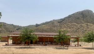 un edificio con mesas y árboles frente a una montaña en Granja escuela con Bungalows, en San Martín de la Vega