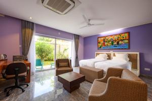 een hotelkamer met een bed, een bureau en stoelen bij Boutique Villa Bougainvillea in Weligama