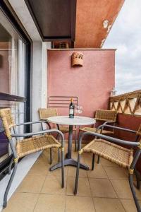 - Balcón con mesa y sillas y botella de vino en Apartamento junto a la playa 4p piscina y parking, en Punta Umbría