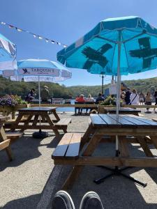 a picnic table with umbrellas on a beach at King of Prussia in Fowey