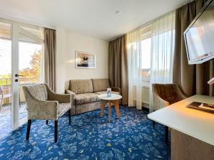 a hotel room with a couch and a table at Hotel-Restaurant Vier Linden in Stade
