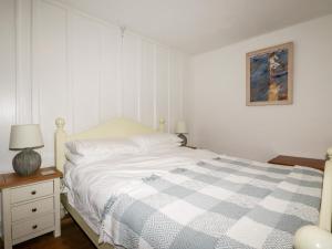 a bedroom with a white bed with a blue and white blanket at Destiny Cottage in Boscastle