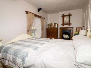een slaapkamer met een wit bed en een open haard bij Destiny Cottage in Boscastle +6 foto's