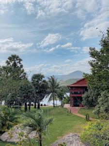 a building with a grassy yard and trees in front at Villa Vedici in Kampot
