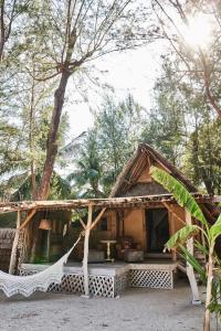 a small house with a hammock in front of it at The Island Houses Gili Meno in Gili Meno