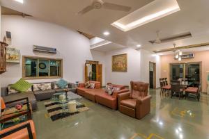 a living room with a couch and chairs and a table at SaffronStays Adora Woods and Hills - 4BHK Murud Villa with Pool, Kids Pool & Beach Fun in Jambrung 
