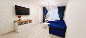 ein Wohnzimmer mit einem blauen Stuhl und einem TV in der Unterkunft A. G. Central Apartaments in Šiauliai