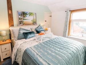 a bedroom with a bed with a blue comforter at Palm Tree Cottage in Great Yarmouth