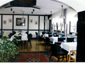 uma sala de jantar com mesas brancas e cadeiras pretas em Kircheiber Hof em Kircheib