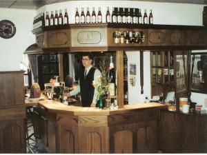 um homem parado atrás de um bar com garrafas de vinho em Kircheiber Hof em Kircheib