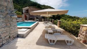 貝西奇的住宿－Luka Villa，一个带椅子和遮阳伞的庭院和一个游泳池