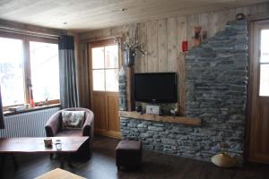 a living room with a tv and a stone wall at Chalet Pomme de Pin in Tignes