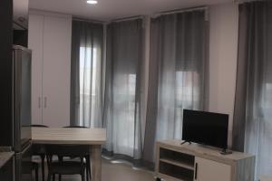 sala de estar con TV y mesa con sillas en APARTAMENTOS AGUAMARINA en Peñíscola