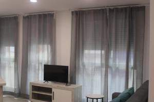 a living room with a flat screen tv on a wooden cabinet at APARTAMENTOS AGUAMARINA in Peñíscola