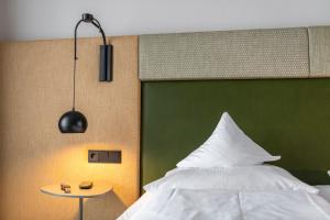 1 dormitorio con 1 cama con cabecero verde y mesa en Hotel Jakob, en Fuschl am See
